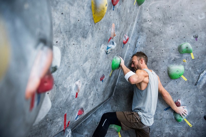 An athletic man climbing on an artificial rock wall.