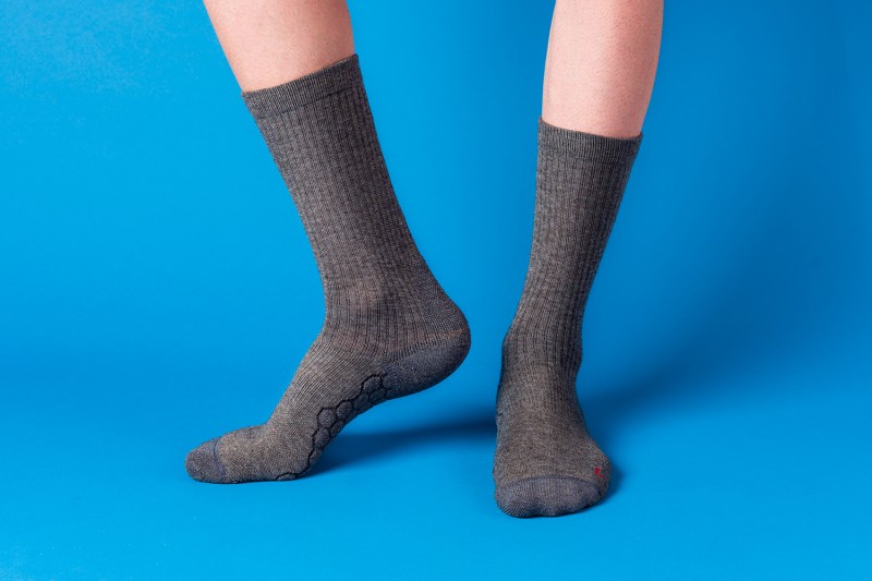 Feet wearing merino wool socks on a blue background.